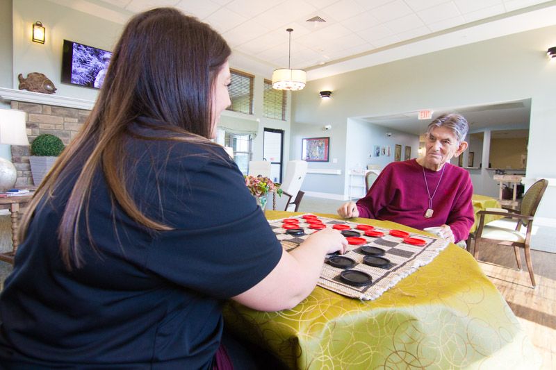 Caregiver playing checkers with memory care resident